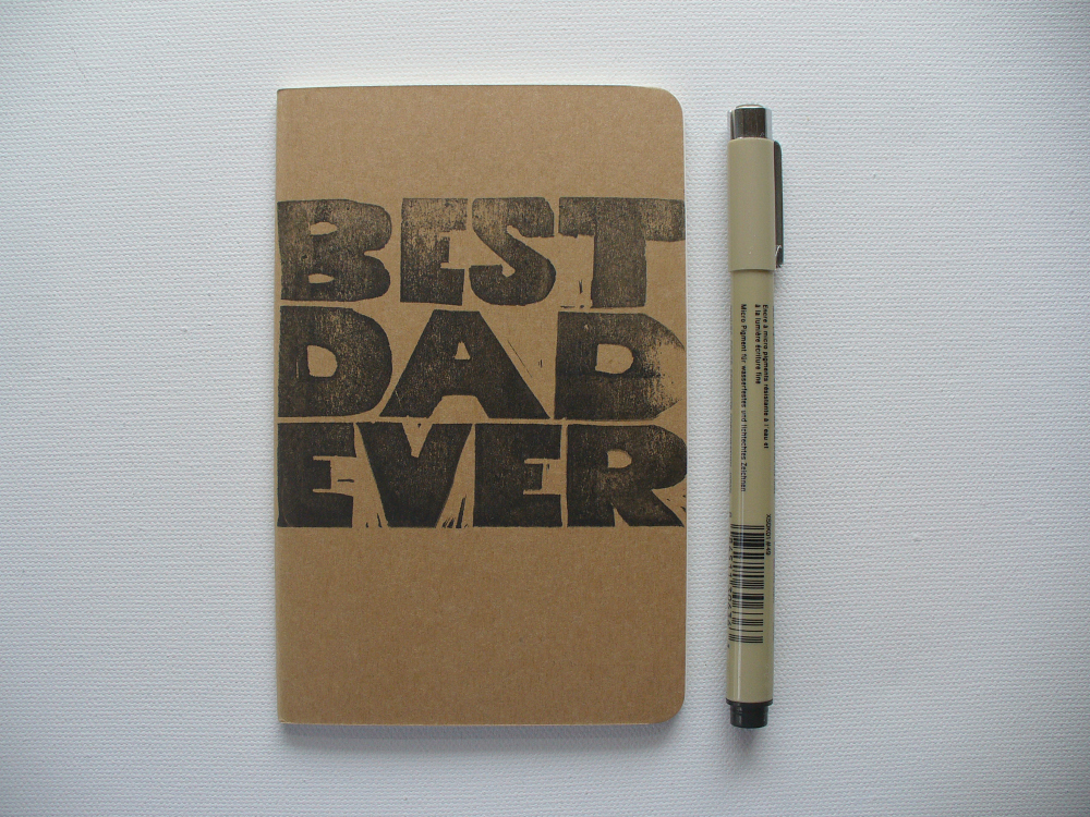 moleskine notebook hand printed with the words best dad ever in black ink