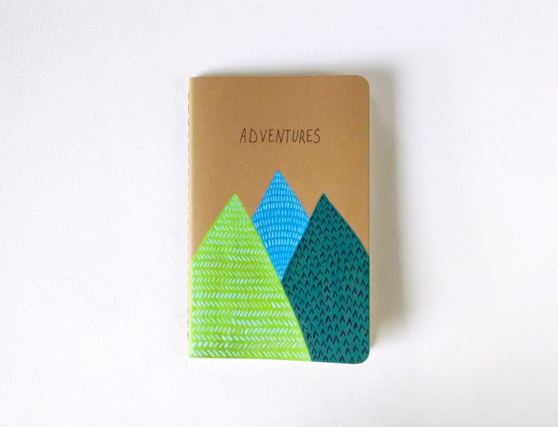 Adventures notebook with hand painted mountains in light green, blue and dark green by messy bed studio