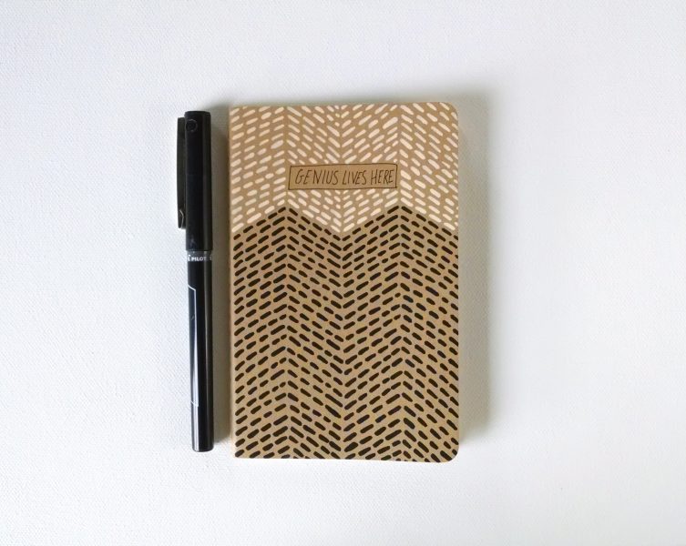 handpainted moleskine notebook with the words genius lives here in a blush and black geometric pattern by messy bed studio