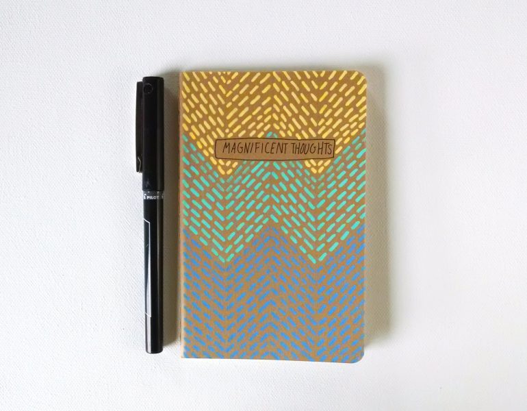 magnificent thoughts moleskine notebook handpainted in a geometric pattern in yellow, aqua and blue by messy bed studio