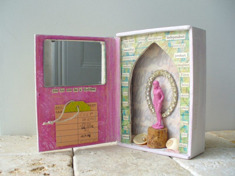 inside view of goddess shrine in pink and green and white with mirror and pink plastic toy of a woman