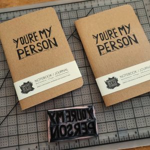 two kraft cover notebooks with the words you're my person in black ink