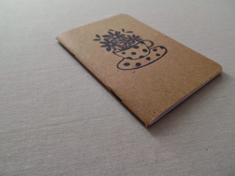 side view of small notebook with kraft cover and image of tea cup and flowers
