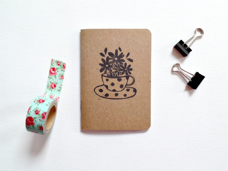 small notebook with image of tea cup and flowers with clips and washi tape