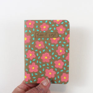 shit list notebook with flowers held in hand