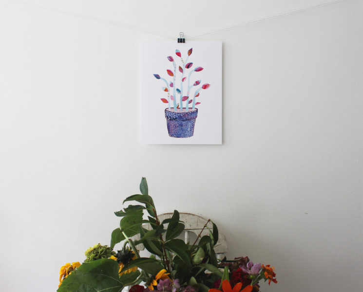 Botanical art print hung on a wall above a bouquet of flowers
