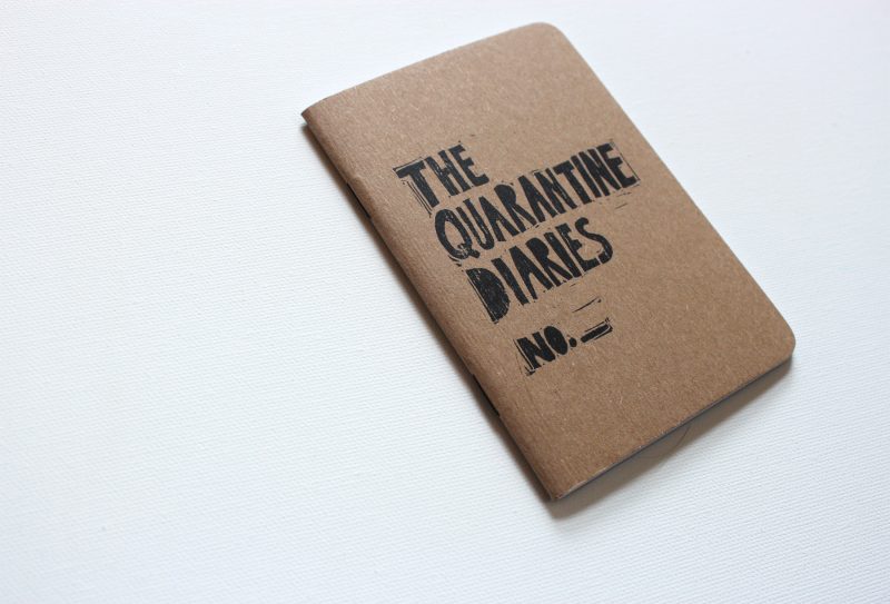 side view of quarantine journal with the words the quarantine diaries hand printed in black ink by messy bed studio