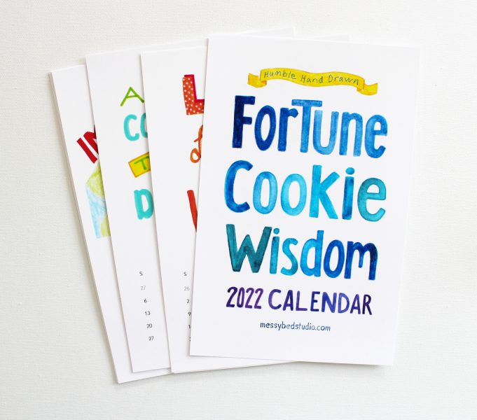 fortune cookie wisdom 2022 calendar cover on top of some interior calendar pages
