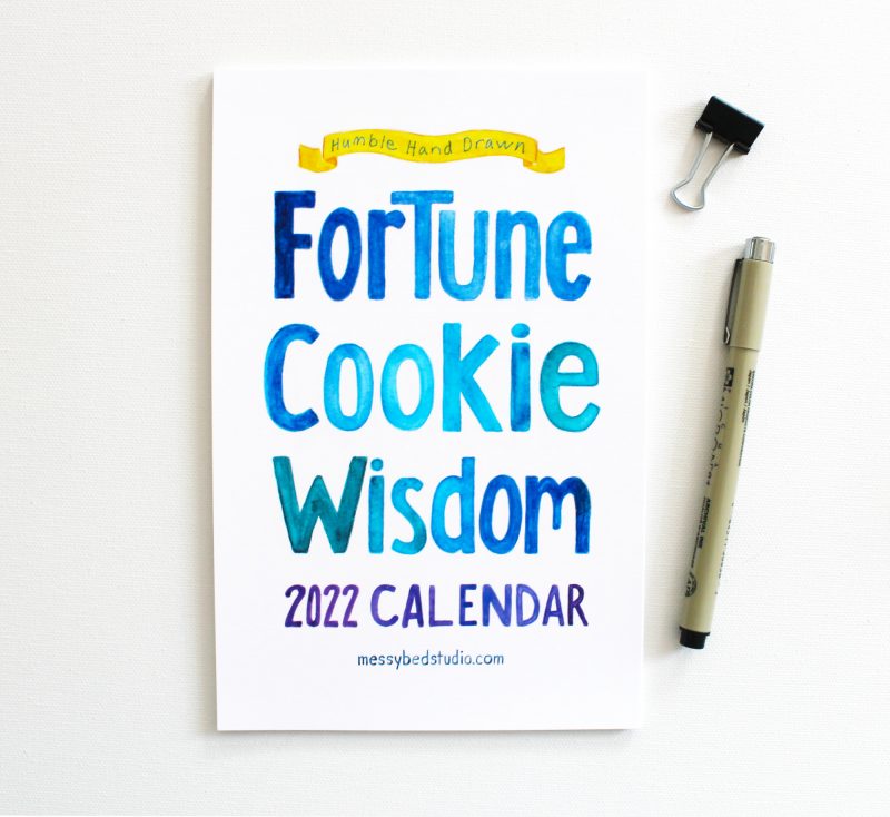 watercolor painted cover of fortune cookie wisdom 2022 calendar with pen and clip shown