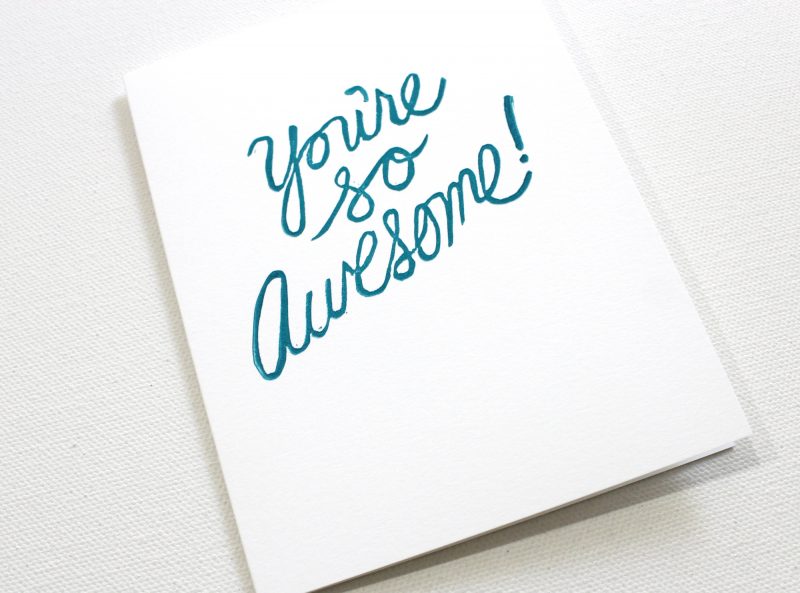 close up of block printed you're awesome cards hand printed in script with turquoise ink