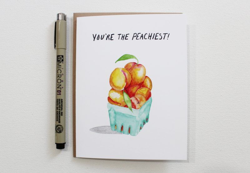 close up view of you're the peachiest thank you card showing watercolor painted peaches piled in a quart container, shown with pen for size